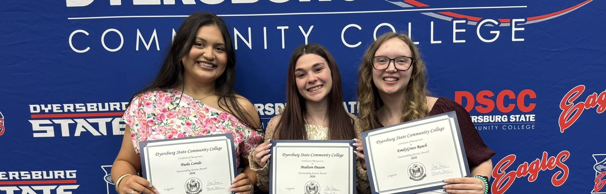 A photo of three SGA Officers smiling in front of a DSCC navy backdrop and holding an award from the Honors Convocation event.