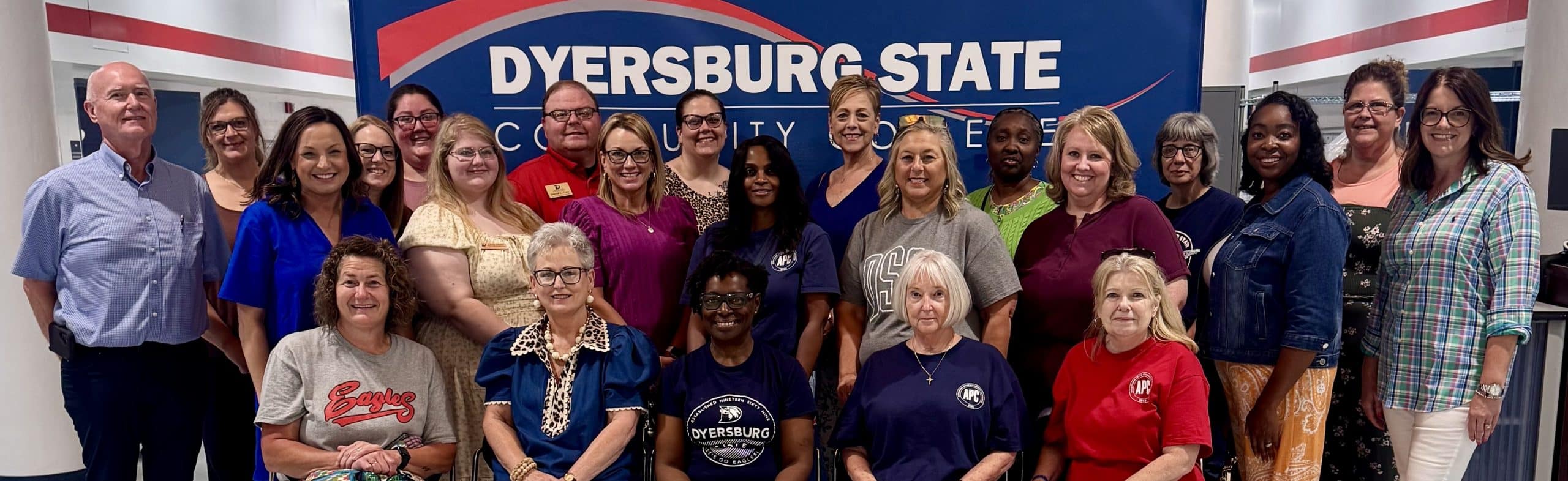 A group photo of the DSCC Administrative Professionals Council members in front of a blue DSCC branded backdrop.