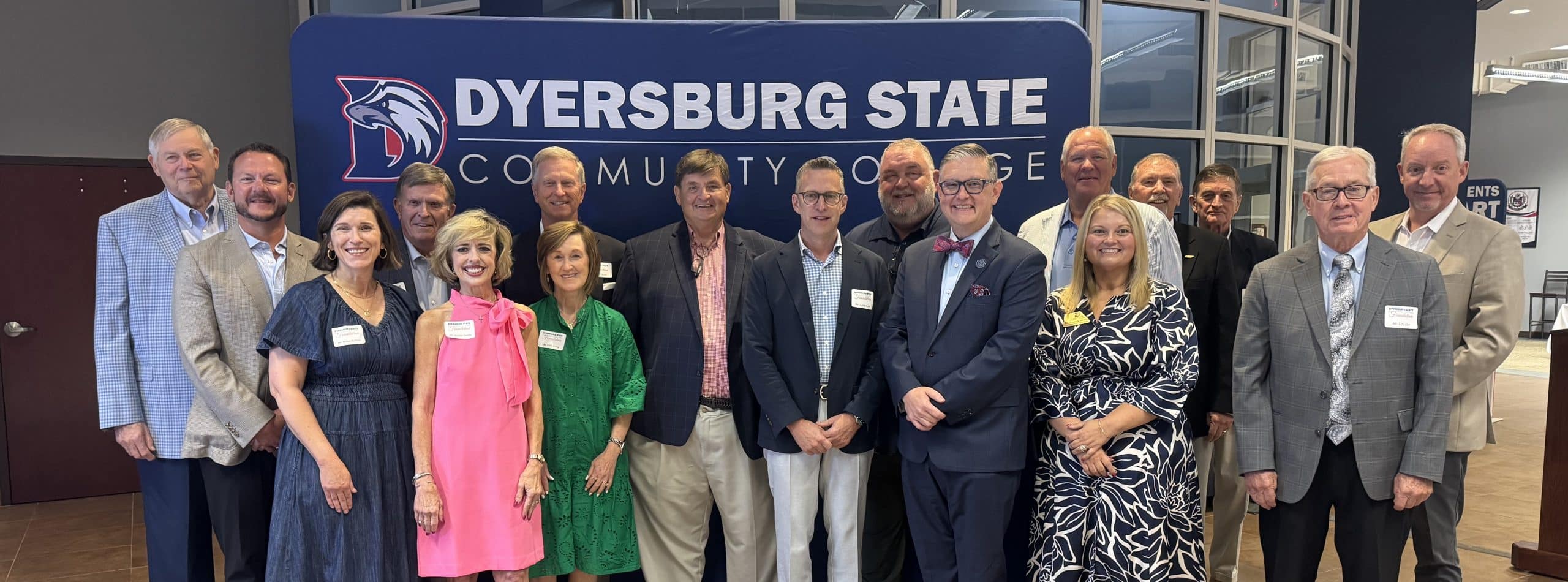 Group photo of the DSCC Foundation Board Members standing inside the DSCC Student Center in front of a blue DSCC-branded backdrop.