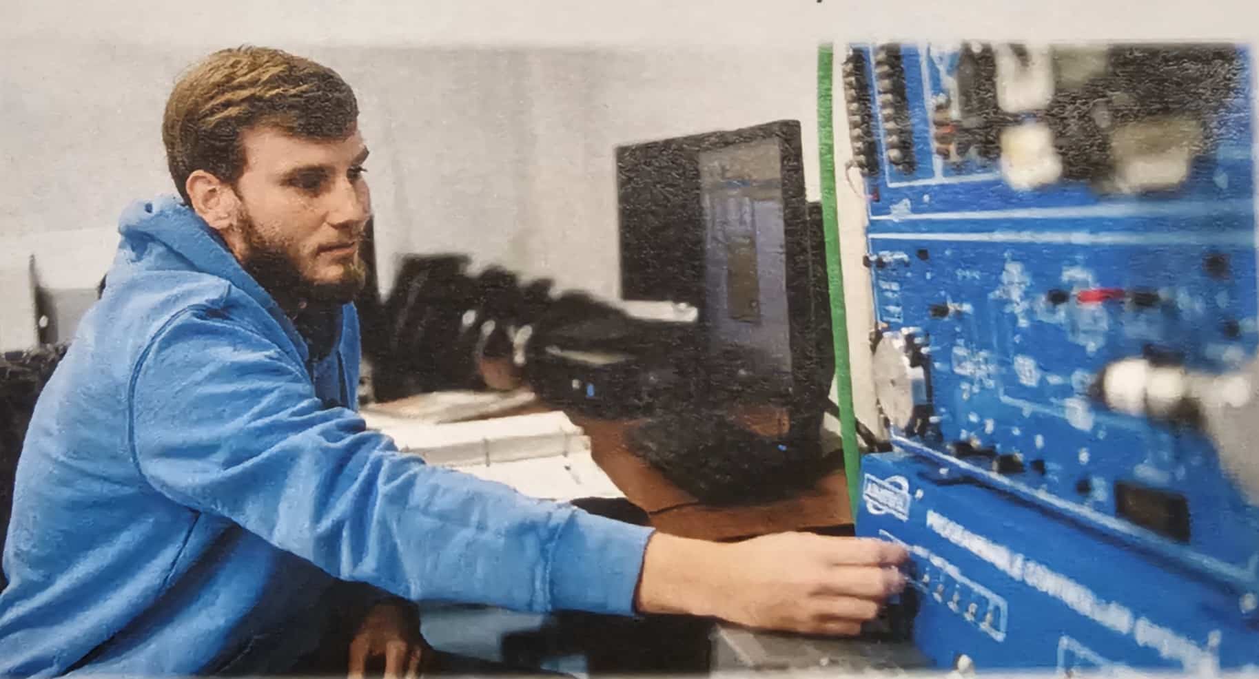 Student working with programmable logic controller (PLC) training equipment in an industrial technology laboratory.