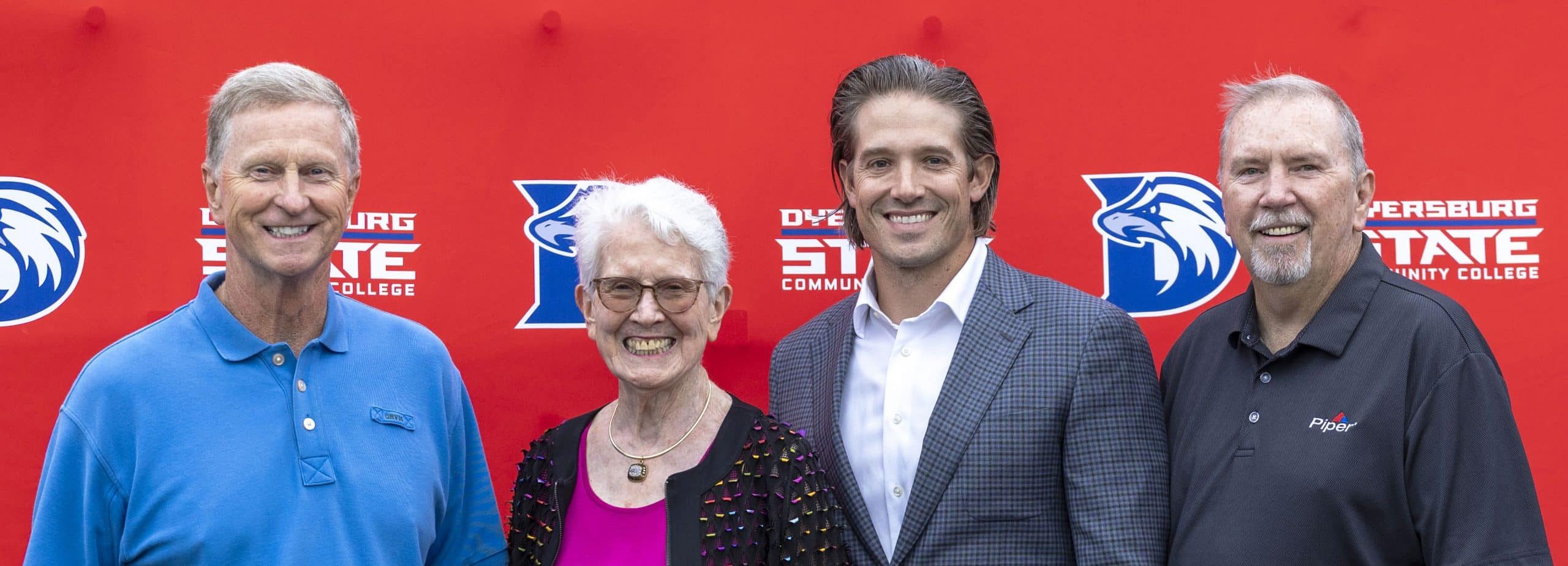 Image of four individuals standing in front of a DSCC red-branded background.
